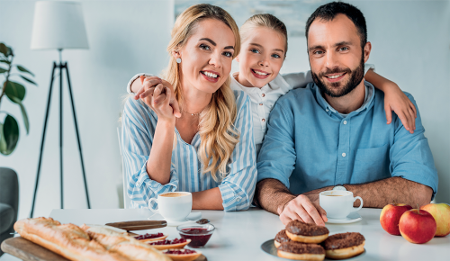 Eine lächelnde Familie an einem Frühstückstisch