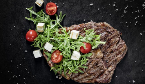 Frisch gebratenes Ribeye-Steak mit Rucola und Cocktailtomaten