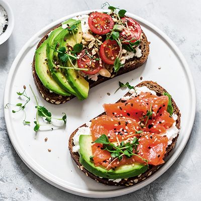 Eine Scheibe Eiweißbrot mit Avocado und eine Scheibe Eiweißbrot mit Räucherlachs