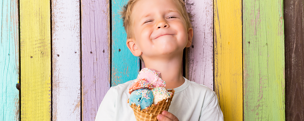 Ein kleiner Junge isst ein buntes Eis im Sommer