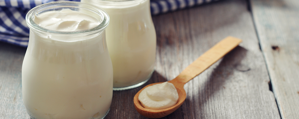Zwei Gläser voller Naturjogurt und ein Holzlöffel