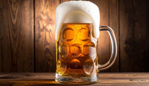Ein voller Masskrug bei dem die Bierkrone etwas über den Glasrand läuft