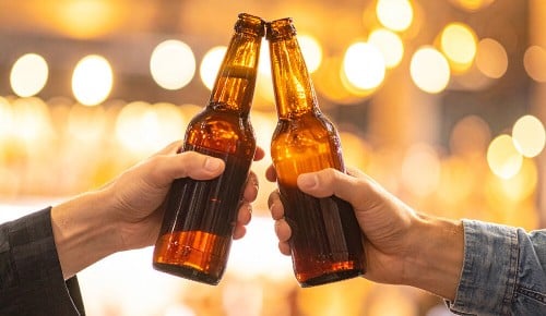Zwei Personen stoßen mit Bierflaschen gemeinsam an
