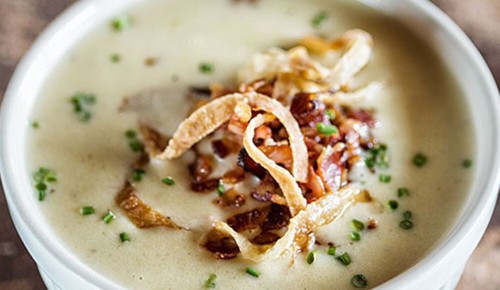 Eine Bier-Käsesuppe mit Röstzwiebeln und Schnittlauch in einem weißen Suppenteller