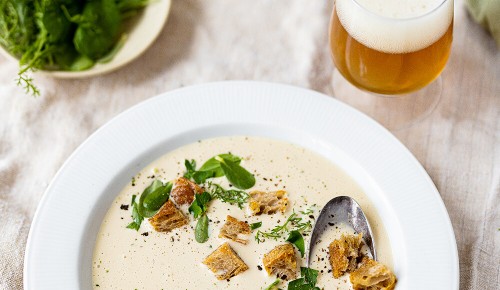 Eine Biersuppe mit Petersilie und Croutons in einem weißen Teller
