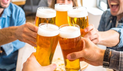 Mehrere Personen stoßen mit vollen Biergläsern miteinander an