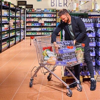 Ein Mann beim Stellen von Bierkartons in einen INTERSPAR-Einkaufswagen