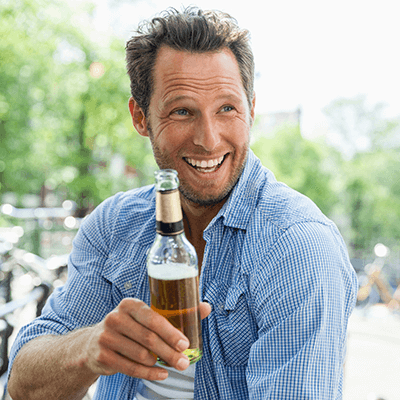 Ein lächelnder Mann mit einer Bierflasche in der Hand