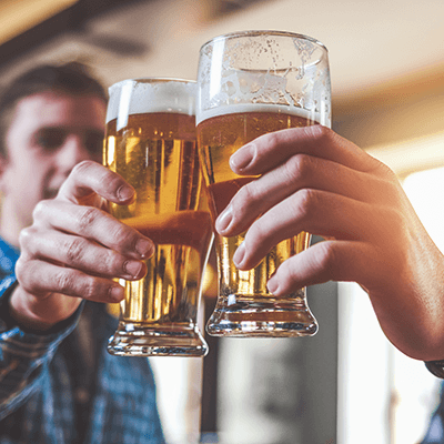 Zwei Personen stoßen mit nicht mehr ganz vollen Biergläsern an