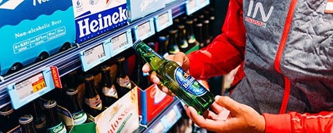 Ein INTERSPAR-Mitarbeiter hält eine Flasche alkoholfreies Bier in den Händen