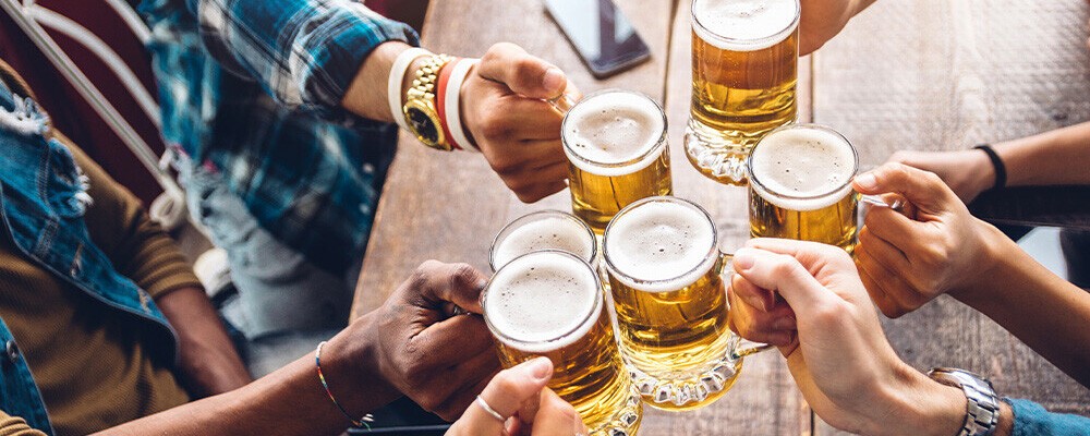 Mehrere Personen stoßen mit vollen Bierkrügen an