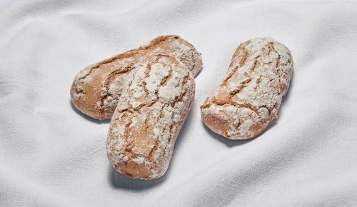 Drei Laib Brot mit einer schönen Kruste auf einem weißen Tuch