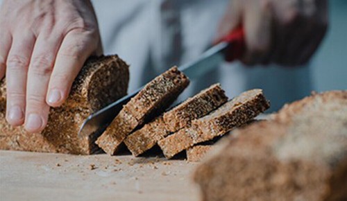Ein Bäcker schneidet mehrere Scheiben Brot