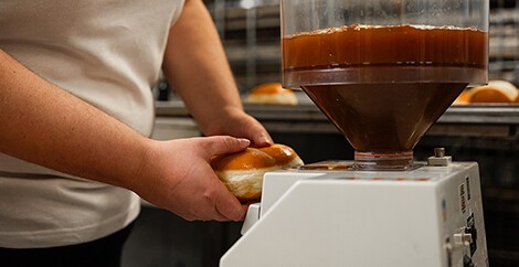 Krapfen wird befüllt mit Marillenmarmelade.