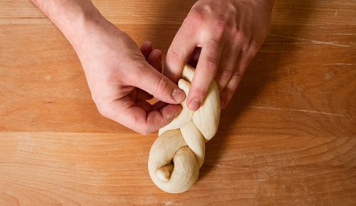 Ein/e Bäcker:in beim Formen eines Striezels mit Germteig