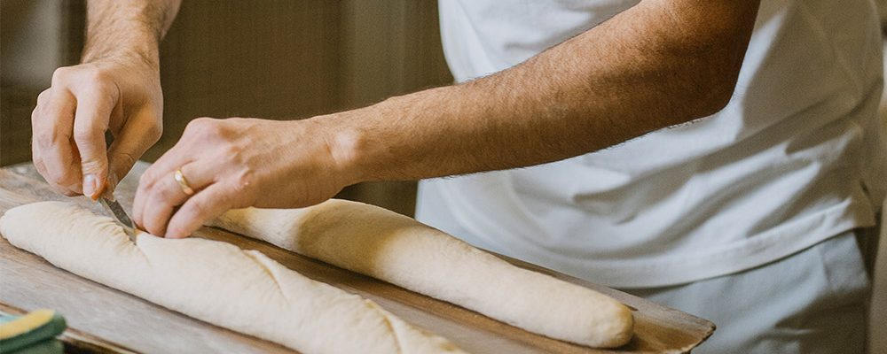 Ein frischer Baguetteteig wird mit einem Messer eingeschnitten