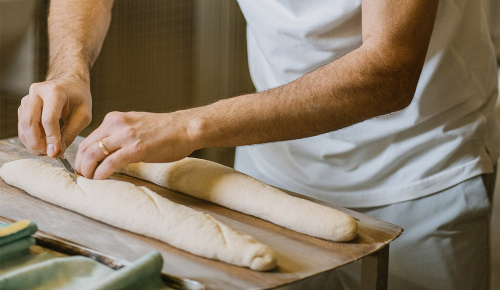 Ein frischer Baguetteteig wird mit einem Messer eingeschnitten