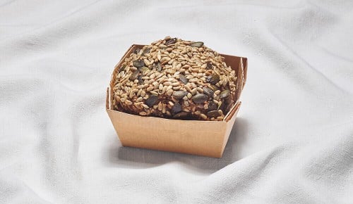 Ein Nur-Kornbrot in einer Pappschale auf einem weißen Tischtuch