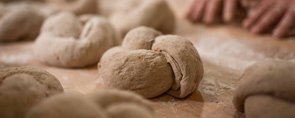 Ein fertig geformter Dinkelknopf beim Rasten auf einem Brett