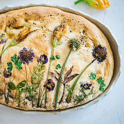 Eine selbstgemachte Focaccia in einer Form mit getrockneten Pflanzen