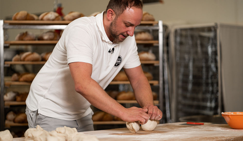 Ein Bäcker beim Wirken eines Baguette-Teiges