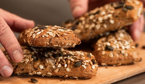 Ein/e Bäcker:in legt fertig gebackene Kraftriegel auf eine Brettchen