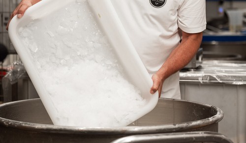 Crushed Ice wird aus einer Wanne in eine große Teigrührschüssel gegeben