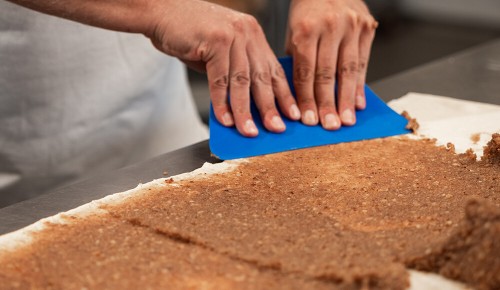 Ein/e Bäcker:in beim Bestreichen eines Teiges mit Nussfüllung
