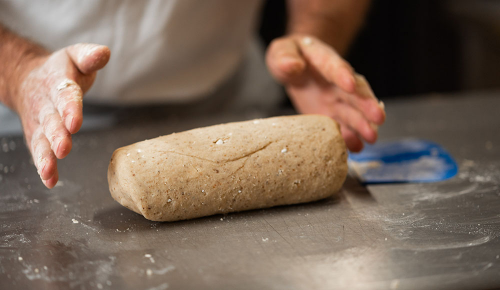 Ein Vanillekipferlteig in einer großen Rolle auf einer Fläche