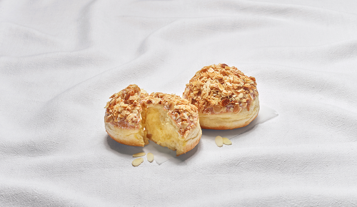 Ein in zwei Hälften geteilter Bienenstichkrapfen auf einem weißen Tuch