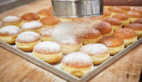 Frische Marillenkrapfen beim bestäuben mit Staubzucker