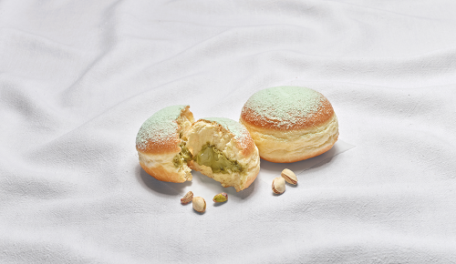 Ein in zwei Hälften geteilter Pistazienkrapfen auf einem weißen Tuch