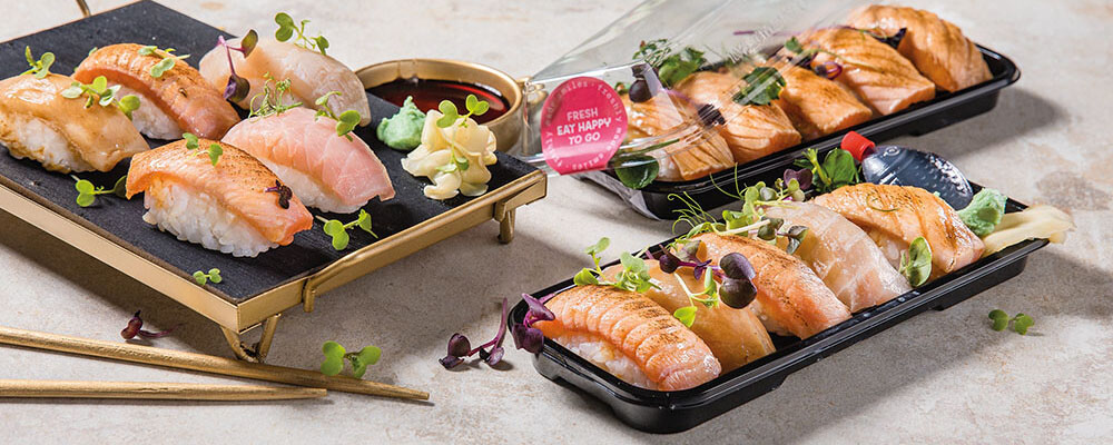 Verschiedene Sushi in To-Go-Boxen verpackt auf einem Tisch