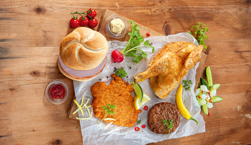 Verschiedene fertige Gerichte wie eine Schnitzelsemmel oder eine Hühnerkeule auf einem Tisch