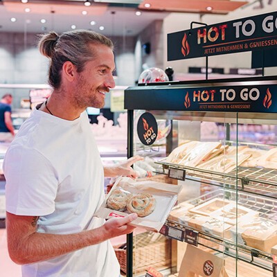 Ein junger Mann beim Auswählen von Hot To Go-Gerichten bei INTERSPAR