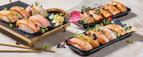 Verschiedene Sushi in To-Go-Boxen verpackt auf einem Tisch