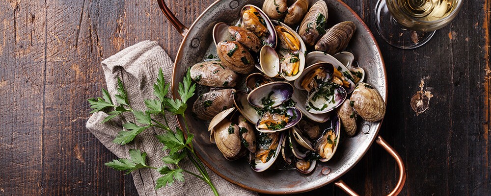 Frisch gekochte Muscheln mit Sud und Kräutern in einem Kochtopf