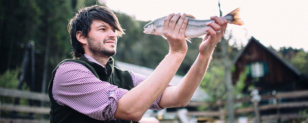 Ein Mitarbeiter von Michis Frische Fische mit einen Fisch in den Händen
