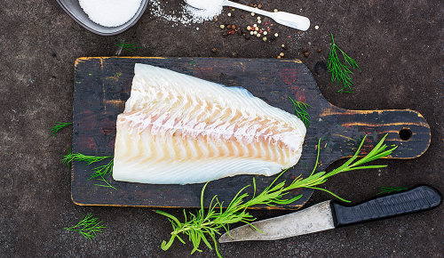 Ein Stück Kabeljaufilet auf einem schwarzen Brett