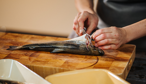 Eine Person beim Filetieren eines Fisches auf einem Brett