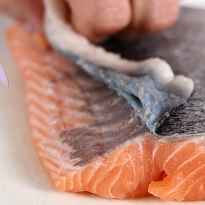 Eine Person beim Entfernen der Haut von einem Stück Lachs