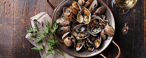 Frisch gekochte Muscheln mit Sud und Kräutern in einem Kochtopf