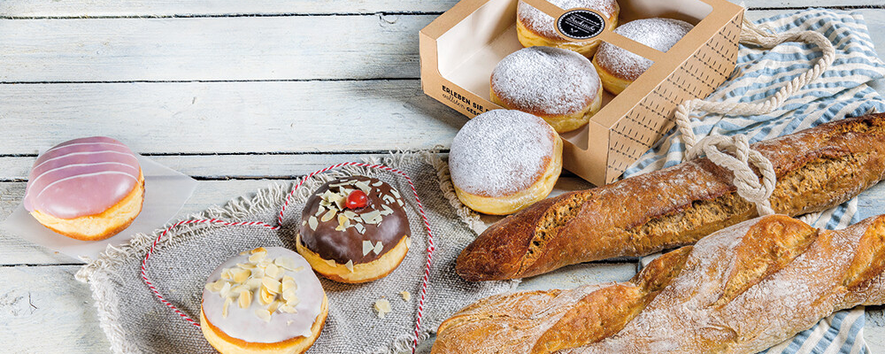Baguettes und verschiedene Krapfen auf einem hellgrauen Untergrund 