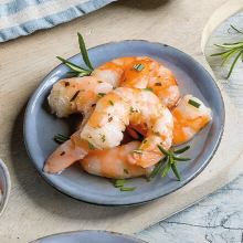 Riesengarnelen mit Knoblauch garniert auf einem blauen Schälchen