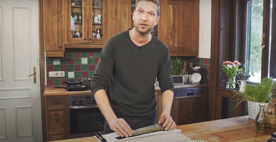 Haubenkoch Didi Maier filetiert Fisch in einer Küche