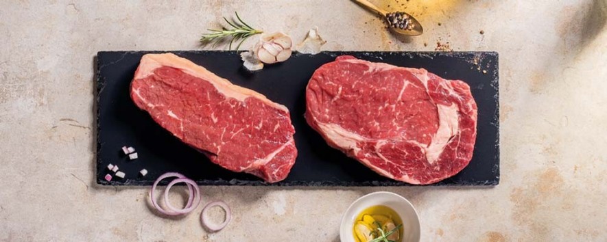 Zwei verschiedene Stücke Fleisch auf einem schwarzen Brett
