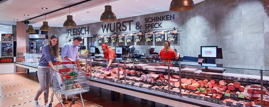 Zwei Personen beim Einkaufen an einer INTERSPAR-Fleischtheke