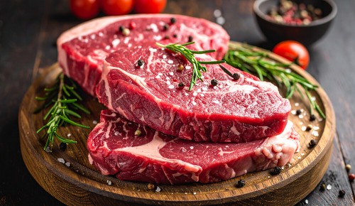 Mehrere Stücke Rindfleisch-Filet garniert mit Rosmarinzweigen auf einem Holzbrettchen