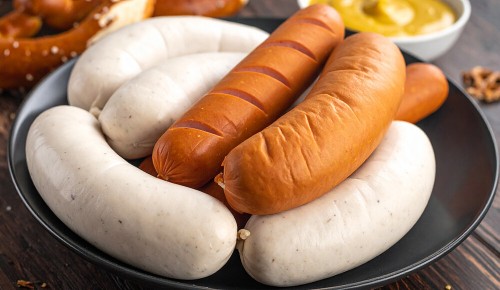 Mehrere verschiedene weiße, braune und helle Würstel in einem dunklen Teller
