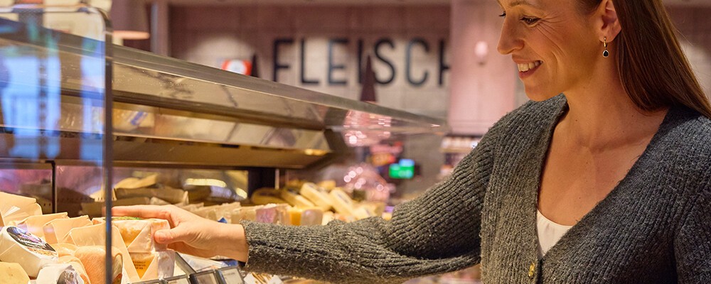 Eine Frau staunt über die große Auswahl an verschiedenen Käse bei INTERSPAR